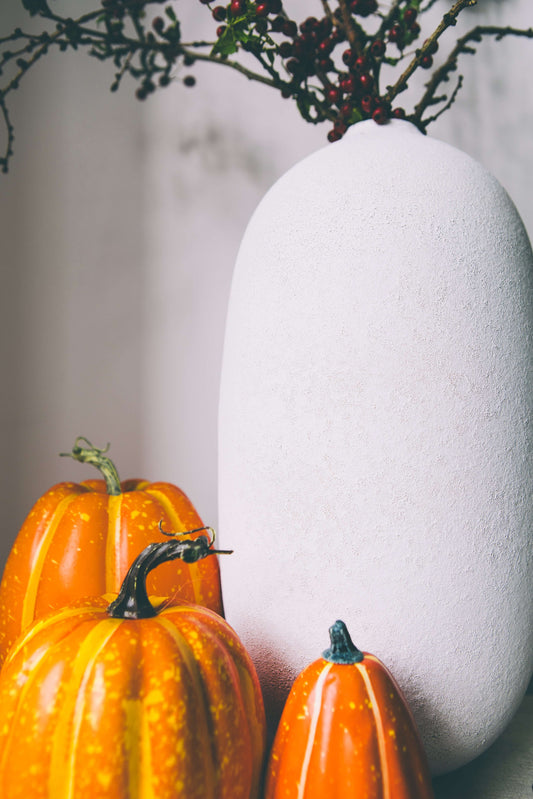 Image of Taylor & Gray white ceramic vase, with aesthetic Halloween decor including orange gourds and pumpkins